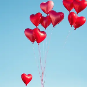 Cluster of Red Heart-Shaped Balloons Against Blue Sky