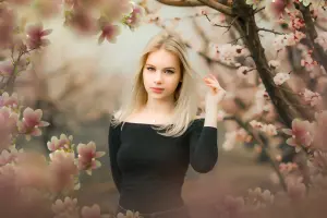 Young Woman in Black Dress Amongst Pink Blossom Trees